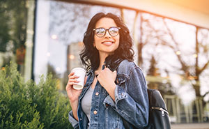 brunette woman with glasses and jean jacket smiling