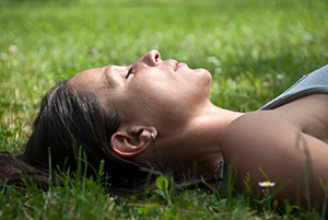 Woman laying down on grass appearing to be sleeping