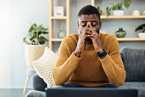 Shot of a young man looking stressed out at home