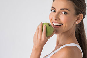 woman eating a green apple and looking at the camera