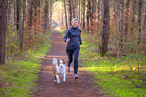 Middle aged Woman running in a running trail with a dog